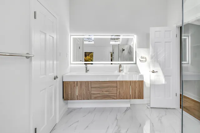 a large bathroom with a glass shower door and a sink
