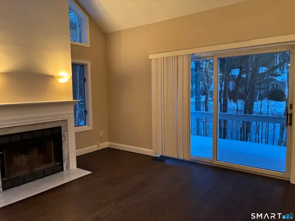 a view of a livingroom with wooden floor a fireplace and window