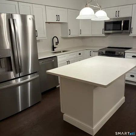 a kitchen with stainless steel appliances a refrigerator a sink a stove and white cabinets