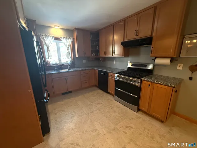 a kitchen with stainless steel appliances granite countertop a stove a sink and a refrigerator