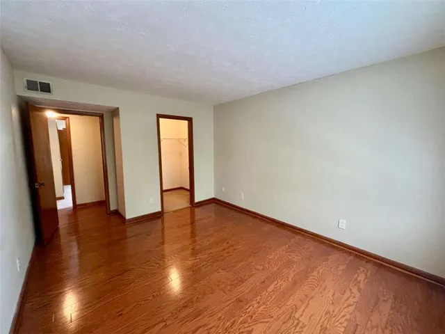a view of an empty room with wooden floor and closet