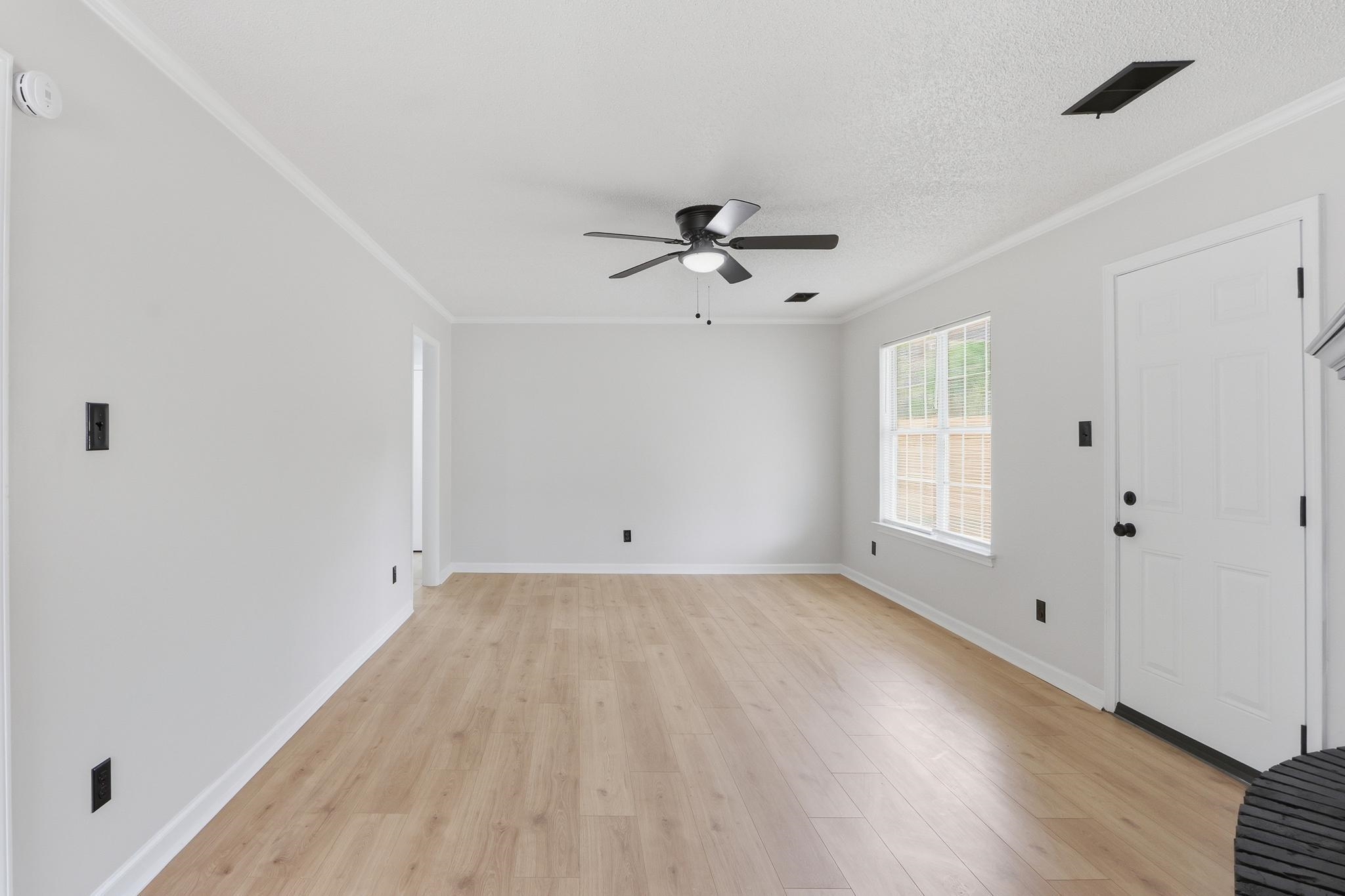 Entrance foyer featuring light wood finished floors, a ceiling fan, crown molding, and a textured ceiling