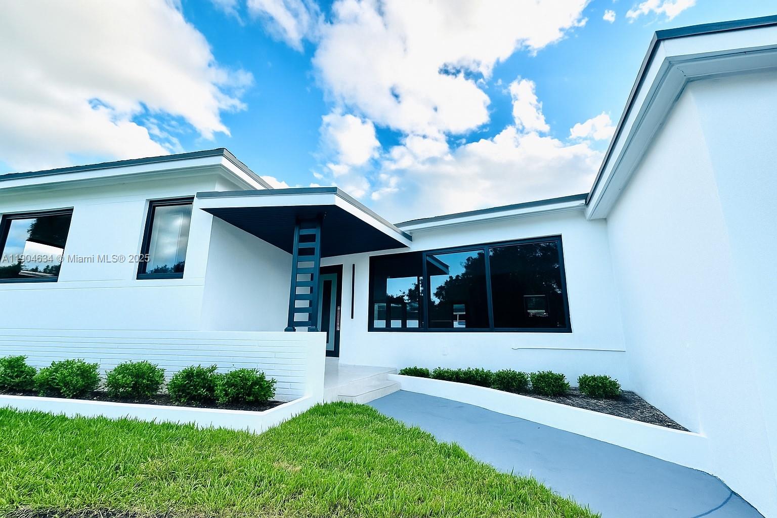 a front view of a house with a yard and potted plants