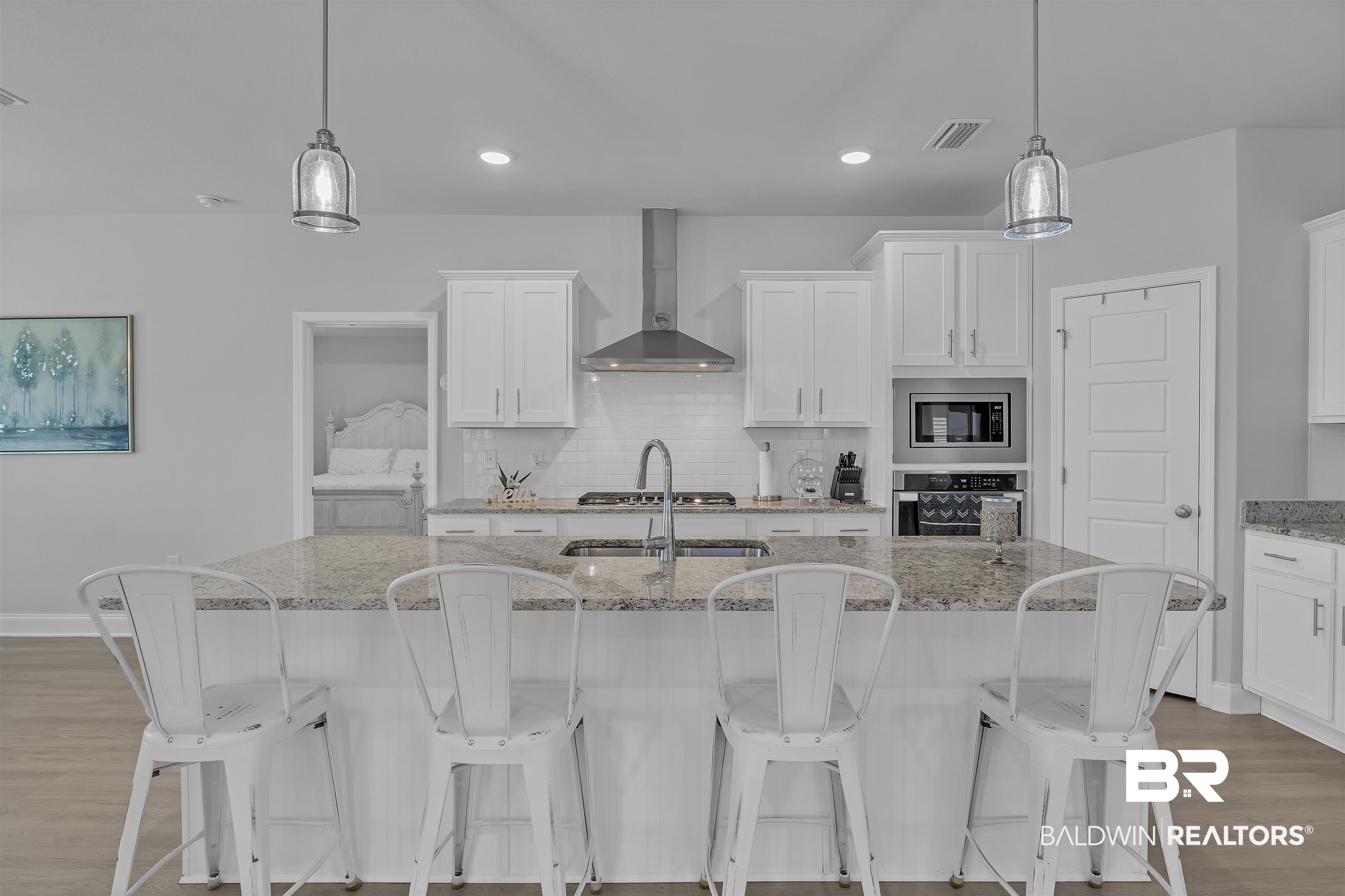 27862 Jade Court Daphne, AL 36526 - Photo 11 of 33 Kitchen featuring wood finished floors, stainless steel appliances, a center island with sink, wall chimney exhaust hood, and white cabinetry