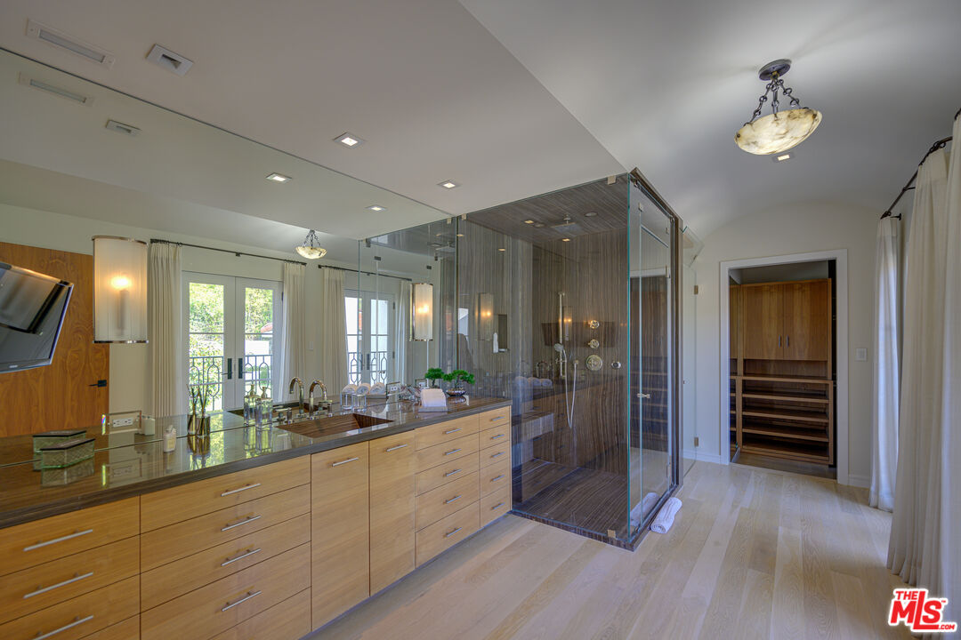 1235 Tower Road Beverly Hills, CA 90210 - Photo 26 of 31 a large bathroom with a large mirror vanity and shower