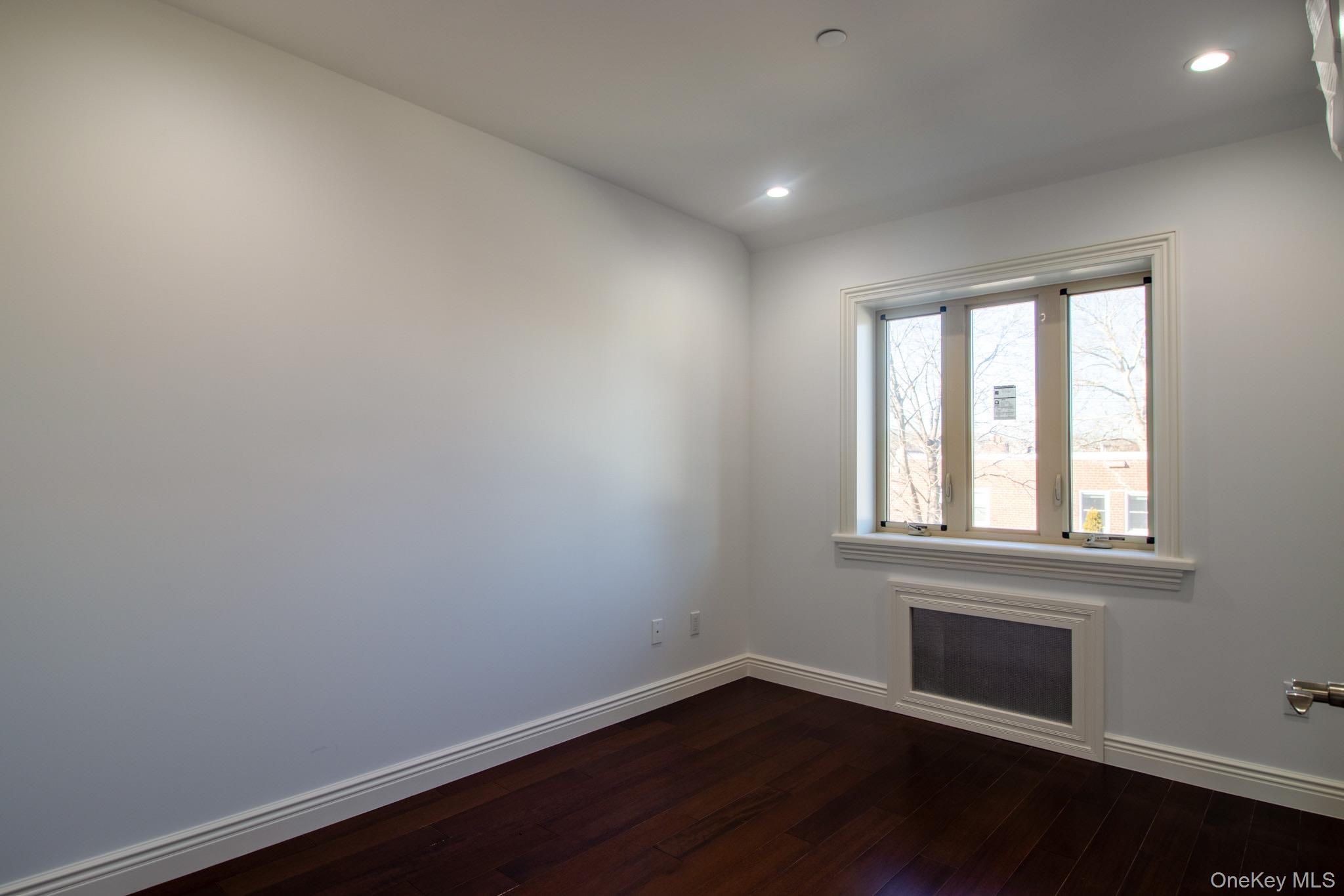 924 129th Street Queens, NY 11356 - Photo 13 of 23 Unfurnished room with dark wood finished floors, recessed lighting, and radiator heating unit