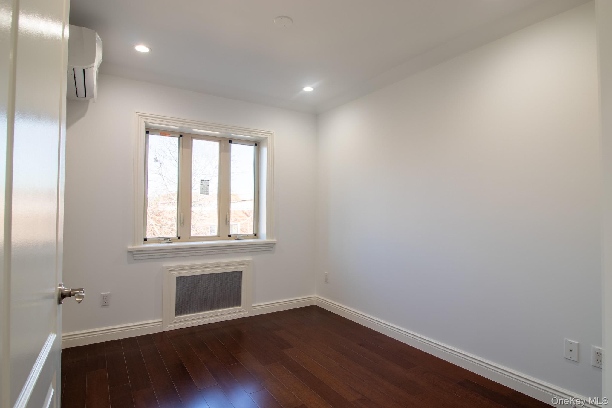 924 129th Street Queens, NY 11356 - Photo 14 of 23 Empty room featuring a wall unit AC, dark wood finished floors, recessed lighting, and radiator