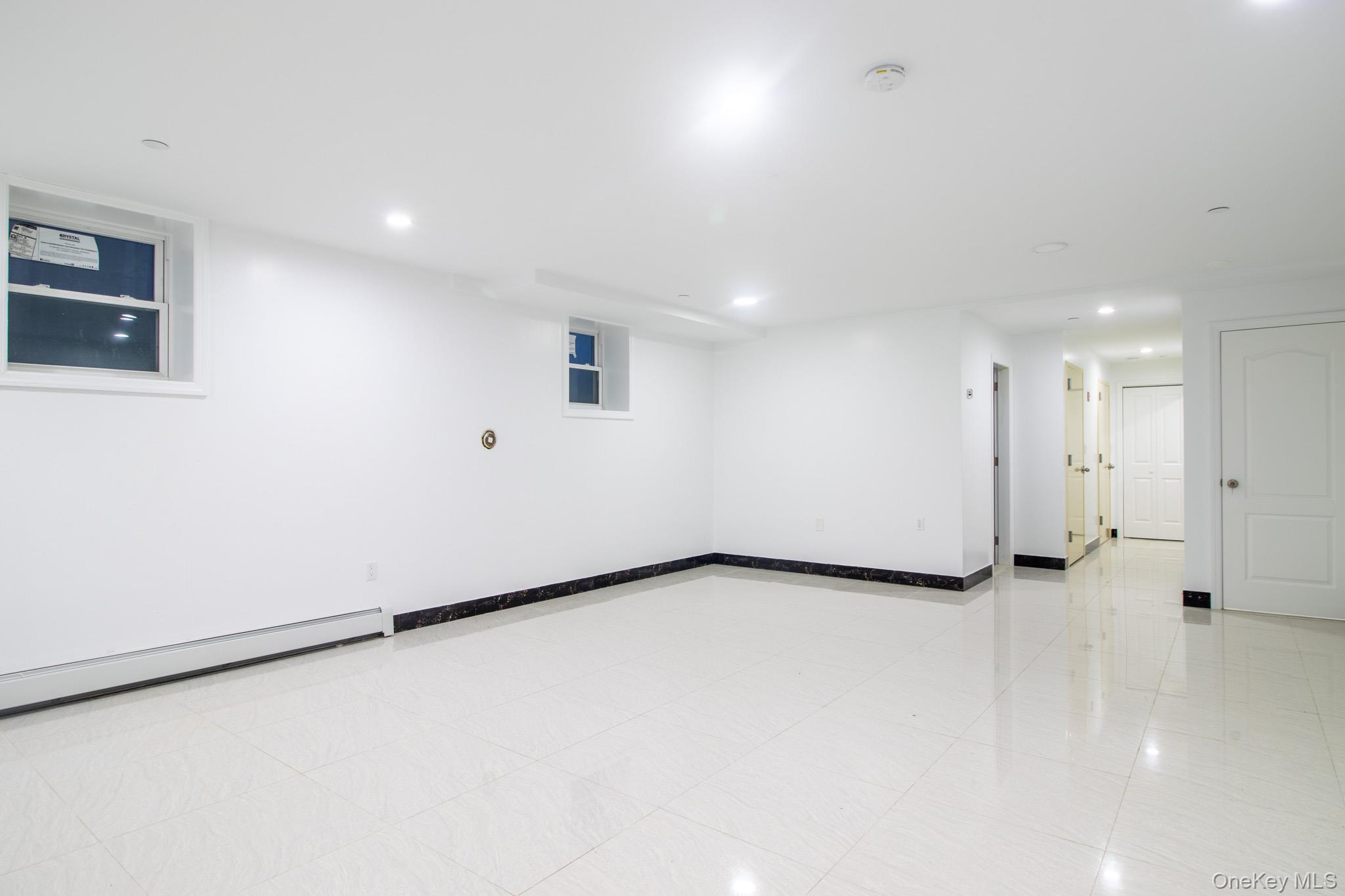 924 129th Street Queens, NY 11356 - Photo 16 of 23 Finished basement with recessed lighting, baseboard heating, and light tile patterned flooring