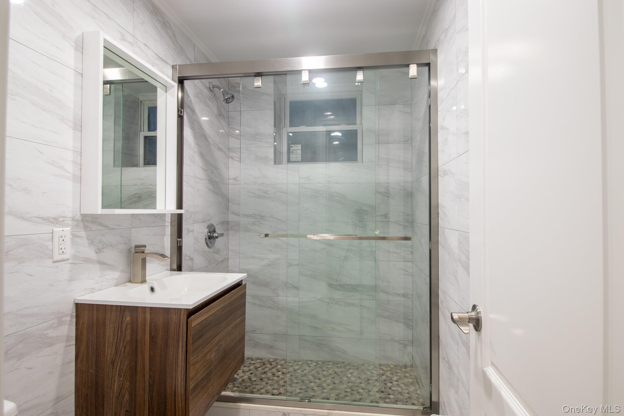 924 129th Street Queens, NY 11356 - Photo 18 of 23 Full bath with vanity, a marble finish shower, and tile walls