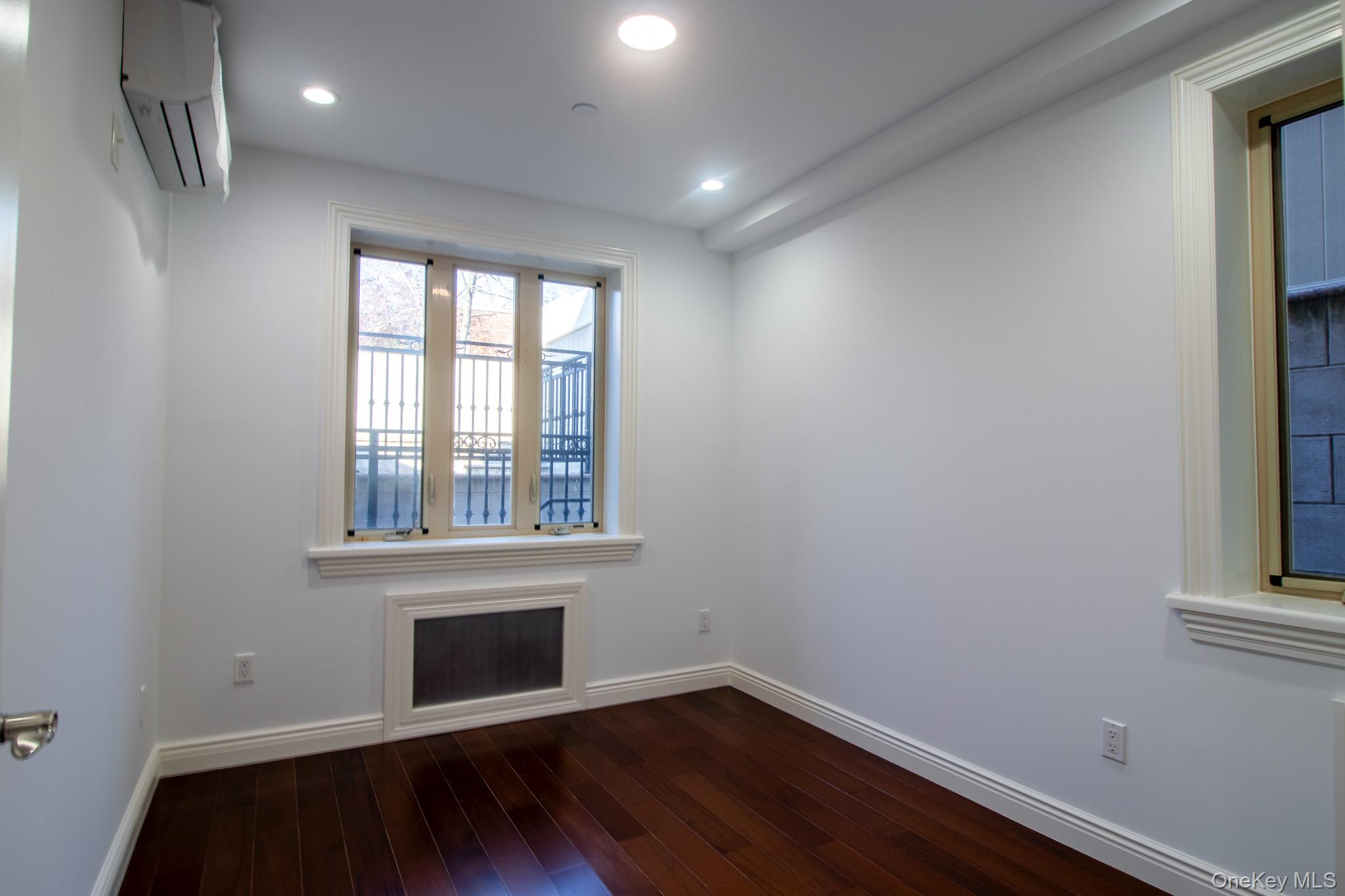 924 129th Street Queens, NY 11356 - Photo 4 of 23 Spare room with an AC wall unit, dark wood-style floors, and recessed lighting