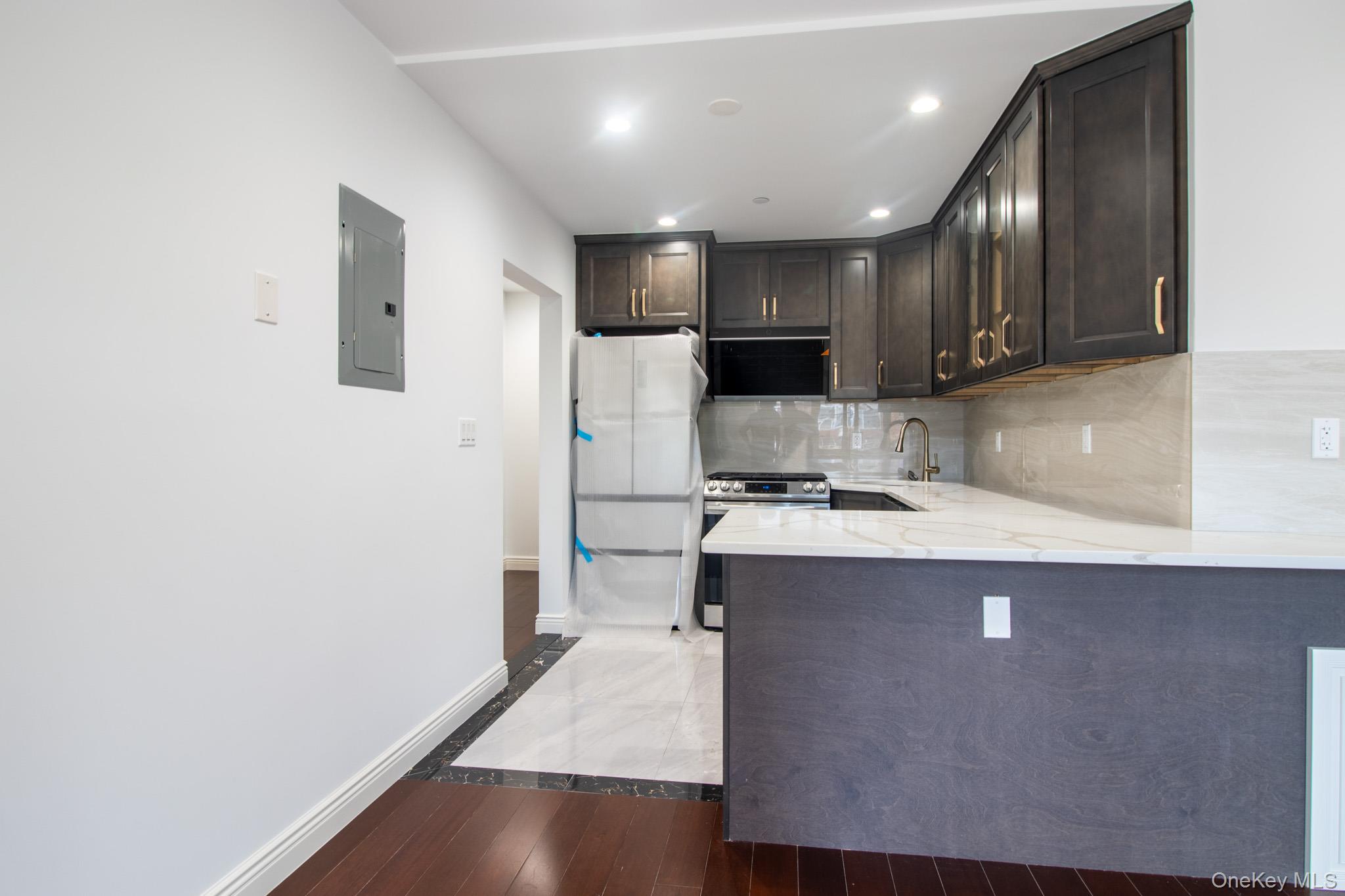 924 129th Street Queens, NY 11356 - Photo 6 of 23 Kitchen featuring dark brown cabinetry, light stone countertops, tasteful backsplash, stainless steel range with gas cooktop, and dark wood-style floors