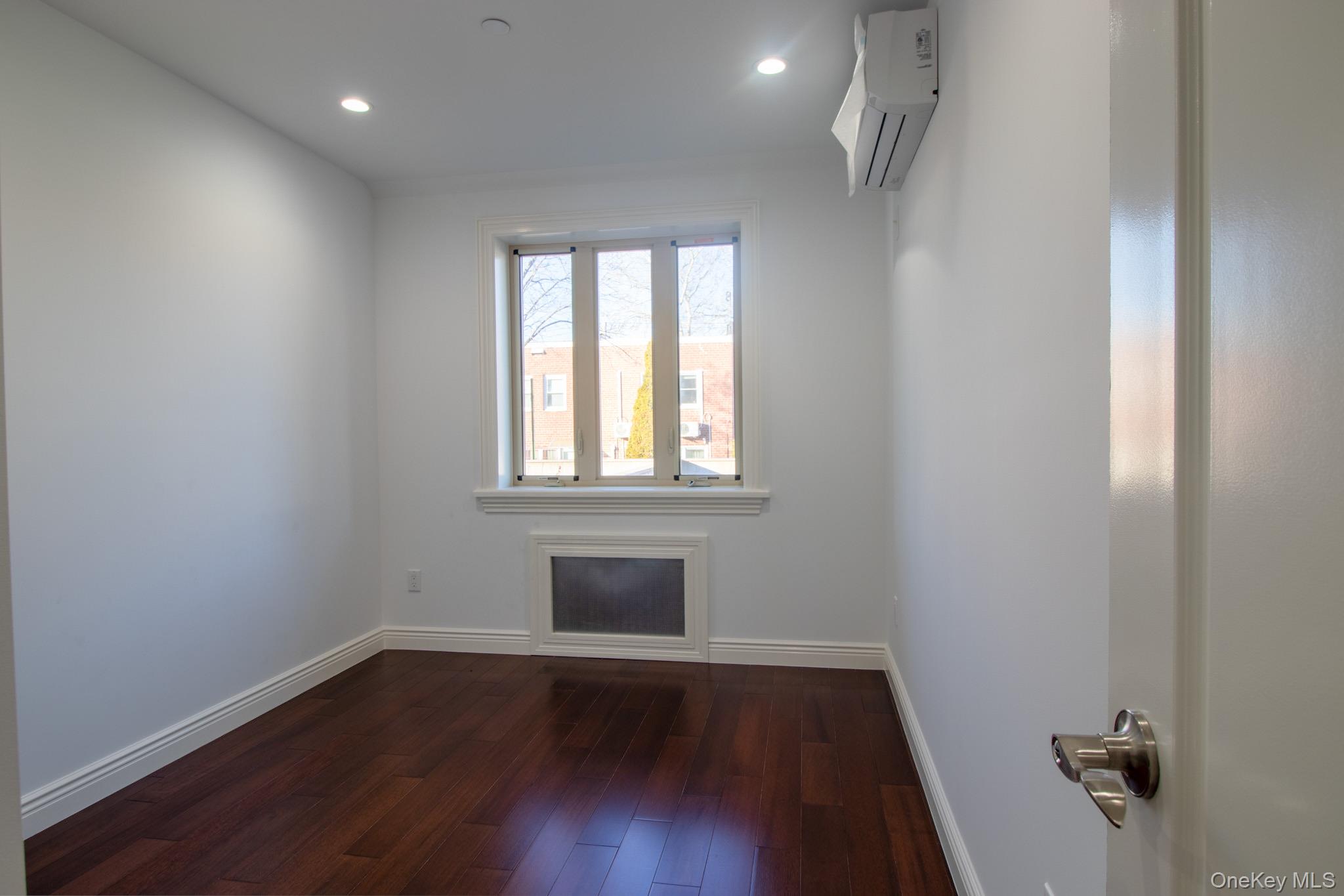 924 129th Street Queens, NY 11356 - Photo 8 of 23 Spare room featuring dark wood finished floors, a wall unit AC, and recessed lighting