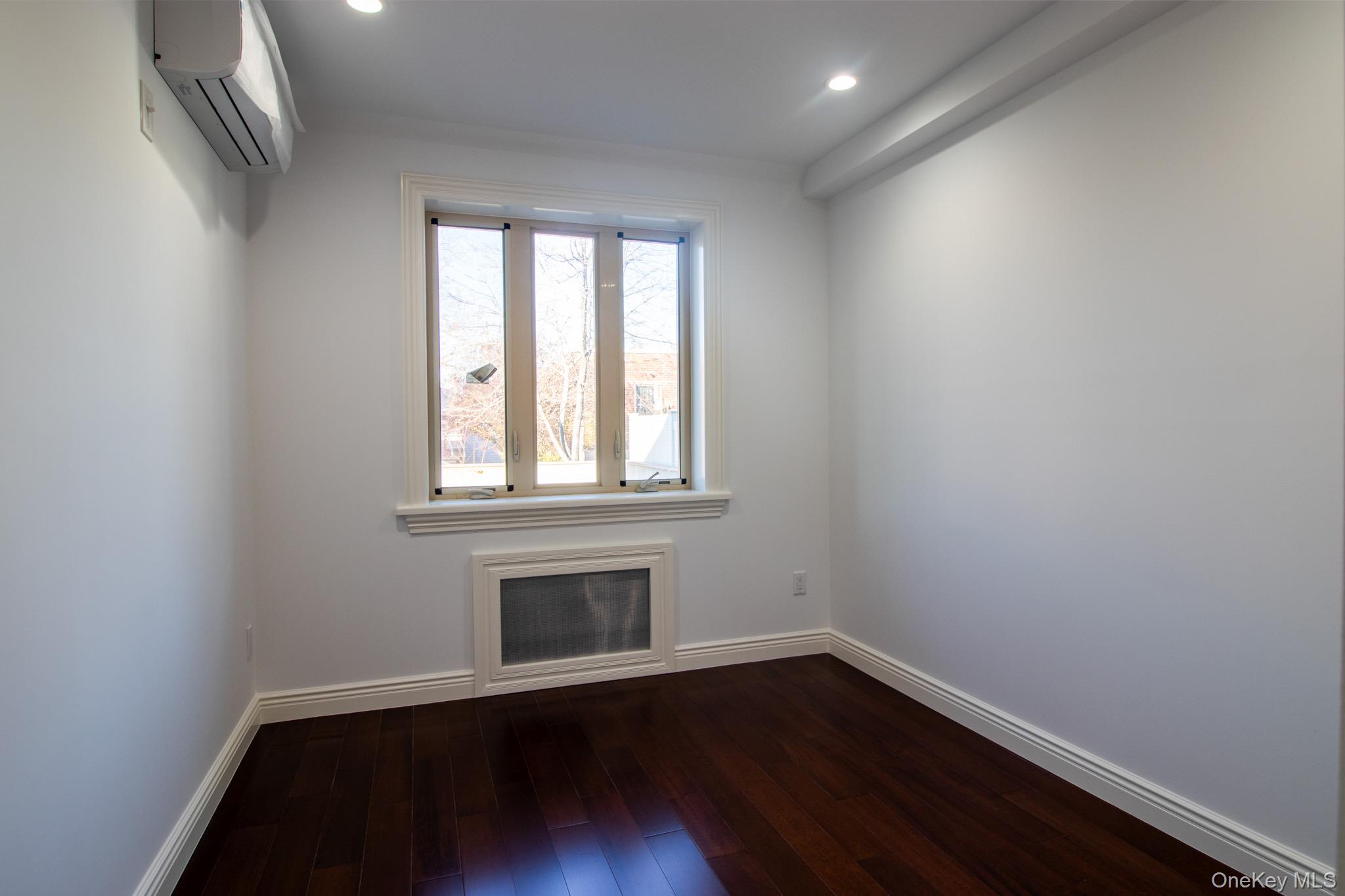 924 129th Street Queens, NY 11356 - Photo 9 of 23 Empty room featuring a wall unit AC, dark wood-style floors, and recessed lighting