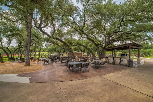 a view of a patio with table and chairs and potted plants and large trees