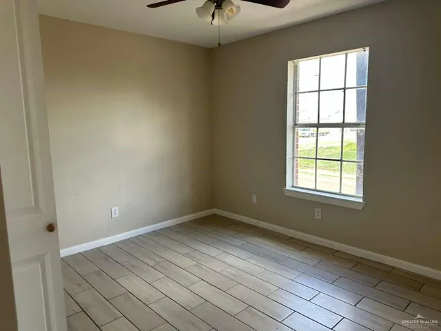 a view of an empty room with wooden floor and a window