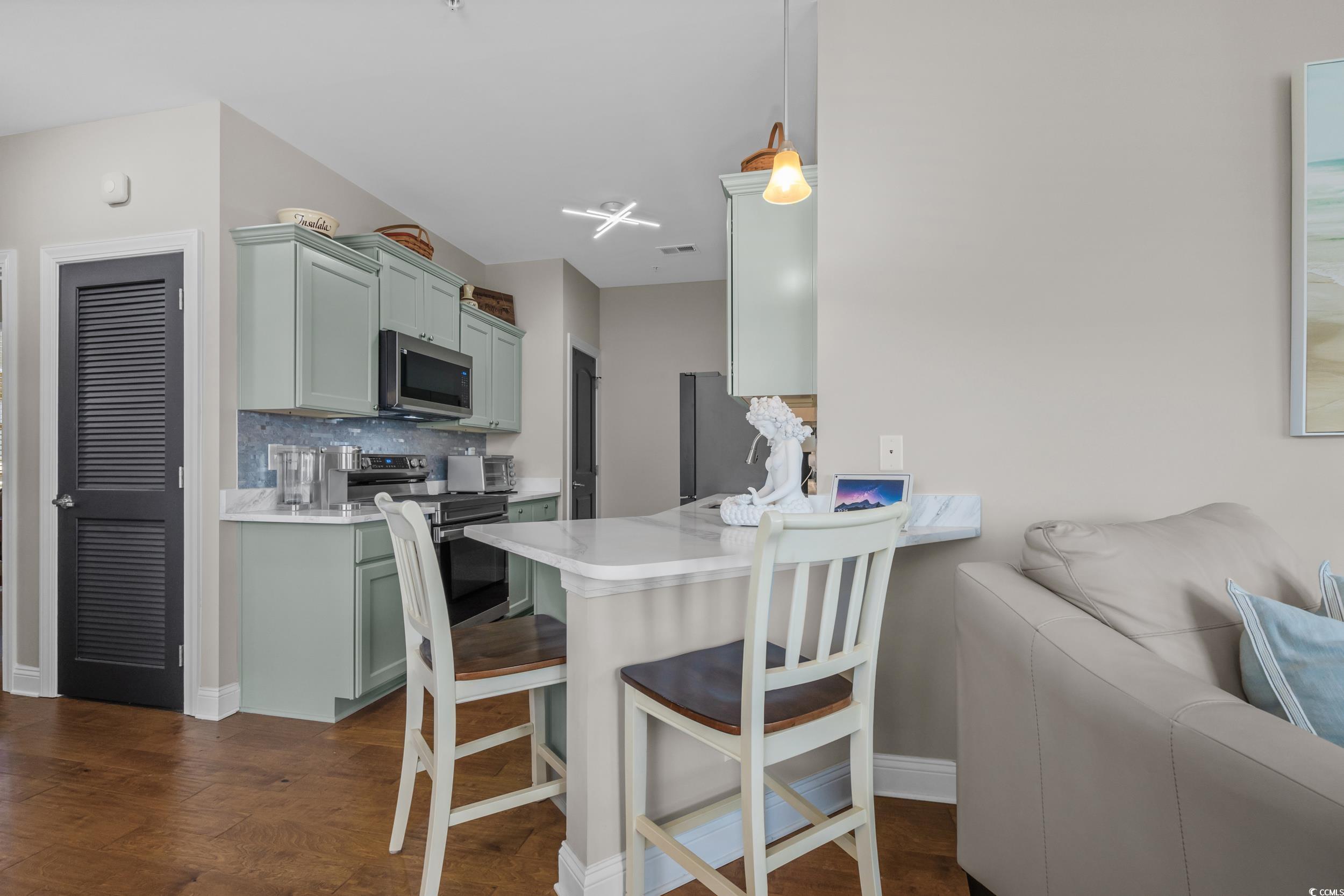 142 Ella Kinley Circle, Unit 304 Myrtle Beach, SC 29588 - Photo 15 of 38 Kitchen featuring a breakfast bar, stainless steel appliances, a peninsula, decorative light fixtures, and decorative backsplash