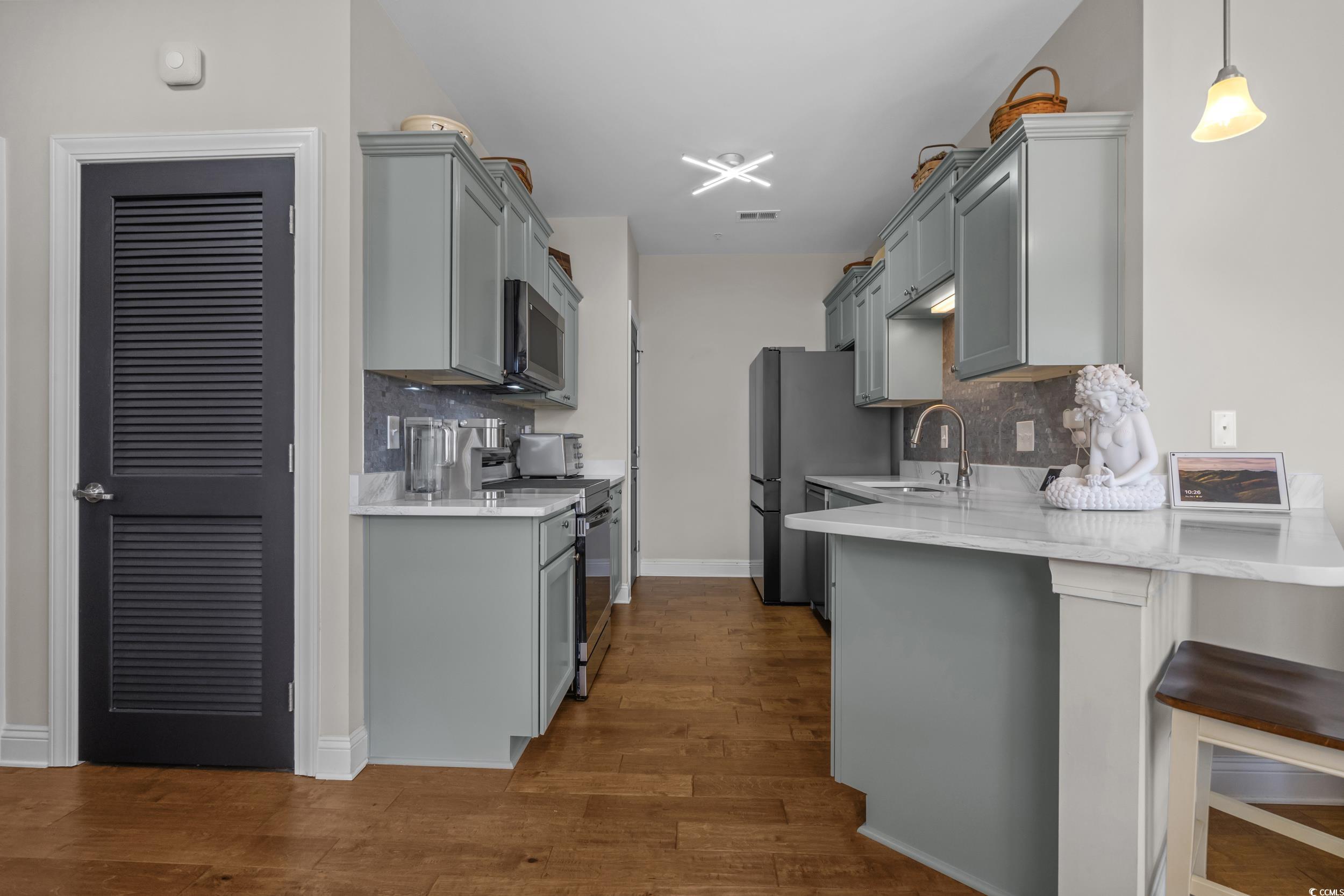142 Ella Kinley Circle, Unit 304 Myrtle Beach, SC 29588 - Photo 16 of 38 Kitchen featuring tasteful backsplash, stainless steel appliances, light stone counters, and gray cabinetry