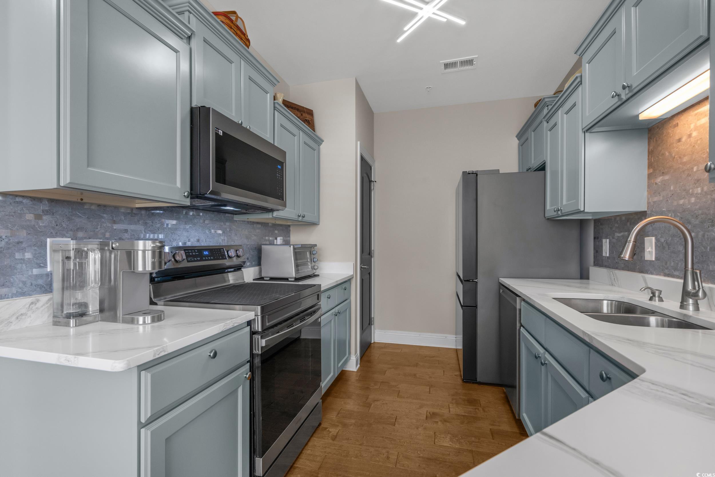 142 Ella Kinley Circle, Unit 304 Myrtle Beach, SC 29588 - Photo 18 of 38 Kitchen with stainless steel appliances, decorative backsplash, light stone countertops, and light wood-type flooring
