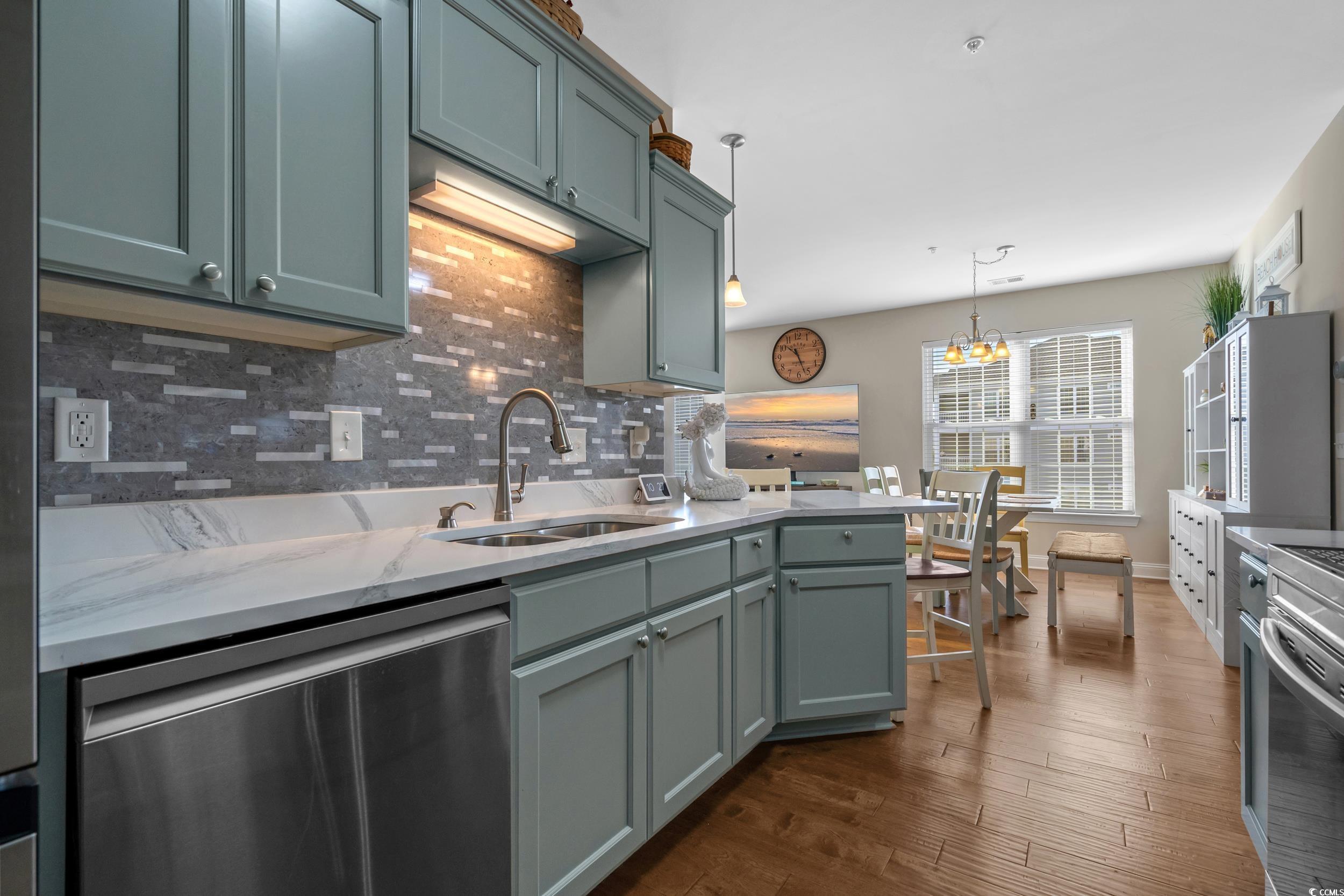 142 Ella Kinley Circle, Unit 304 Myrtle Beach, SC 29588 - Photo 19 of 38 Kitchen with decorative backsplash, stainless steel appliances, hanging light fixtures, dark wood-style floors, and light stone counters