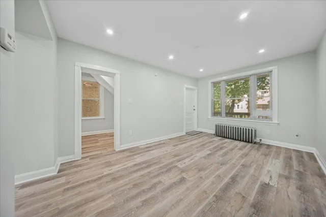 a view of an empty room with wooden floor and window