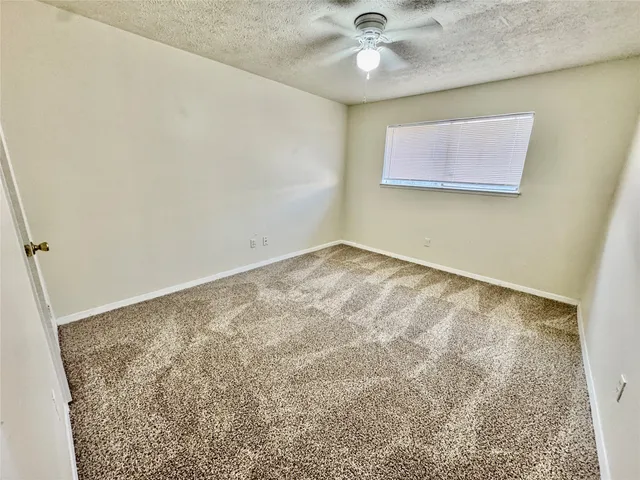 an empty room with a ceiling fan and carpet