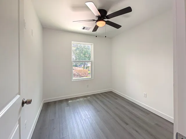 an empty room with a window and a fan