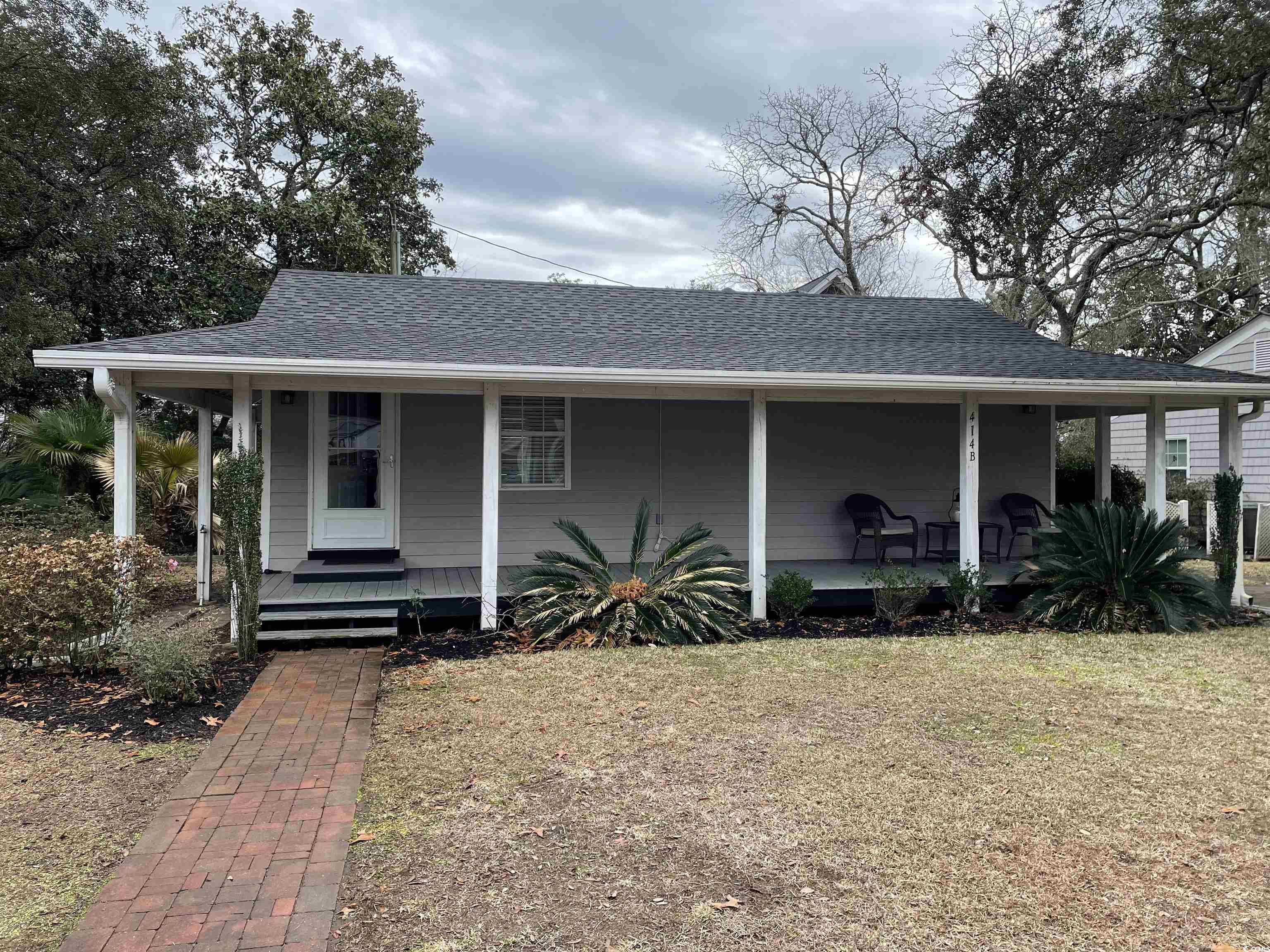 View of front facade with roof with shingles, a large porch, and a front yard