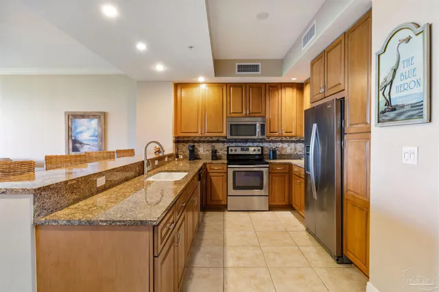 a kitchen with granite countertop a sink stainless steel appliances and cabinets