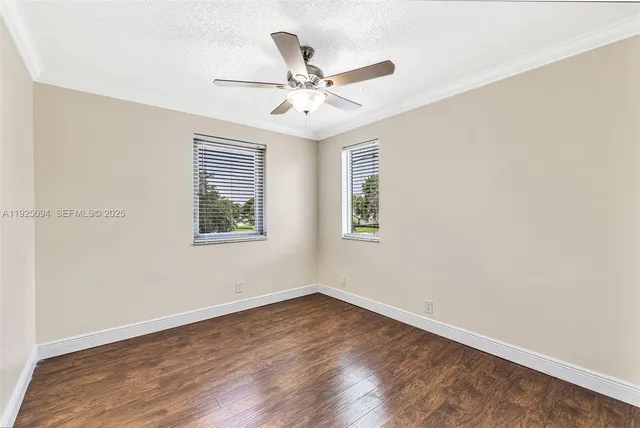 an empty room with wooden floor fan and windows