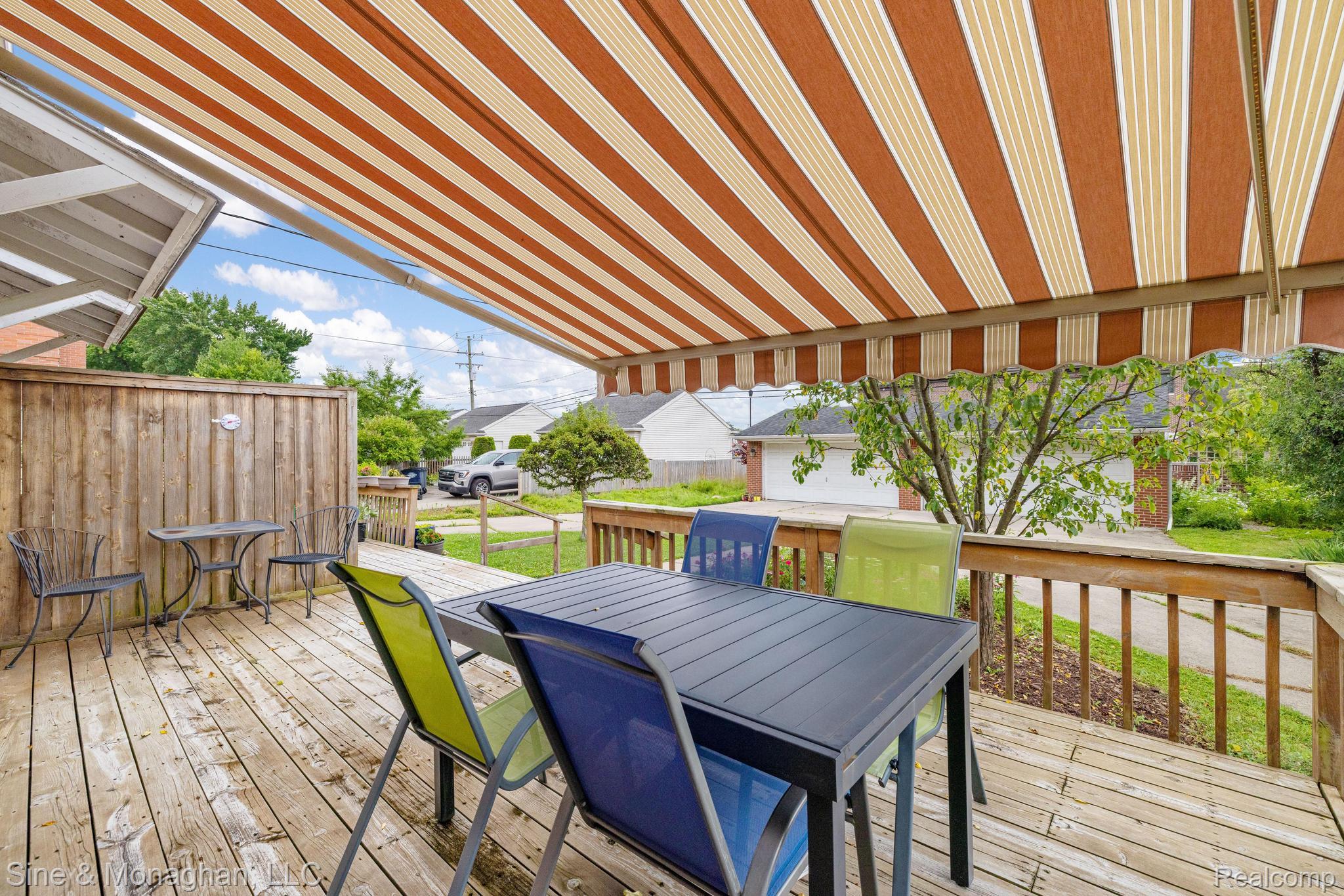 679 Neff Road Grosse Pointe, MI 48230 - Photo 41 of 78 Wood-finish deck with a striped retractable awning, wood railing, and privacy fencing