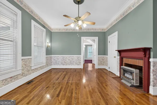 a room with chandelier fan and wooden floor