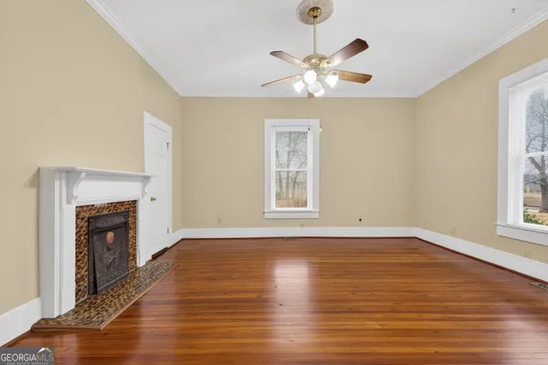 a view of an empty room with wooden floor and a window