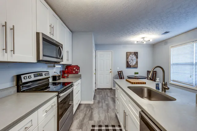 a kitchen with stainless steel appliances a stove a sink a microwave and cabinets