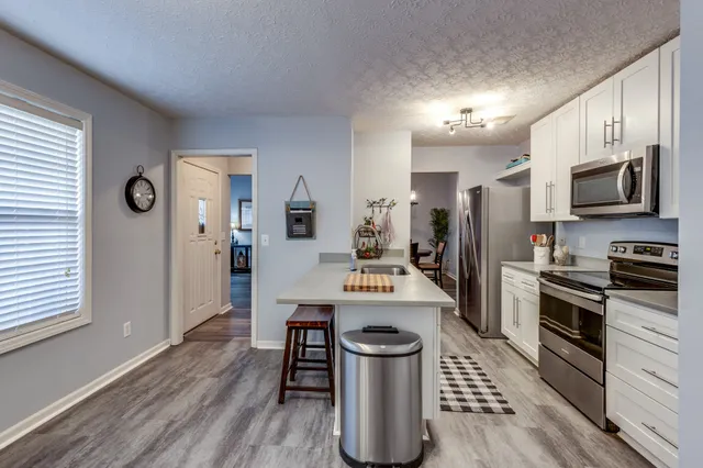 a kitchen with a refrigerator a stove top oven a sink dishwasher and dining table with wooden floor