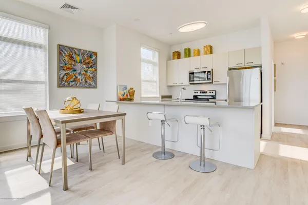 a kitchen with stainless steel appliances granite countertop a dining table chairs refrigerator and sink