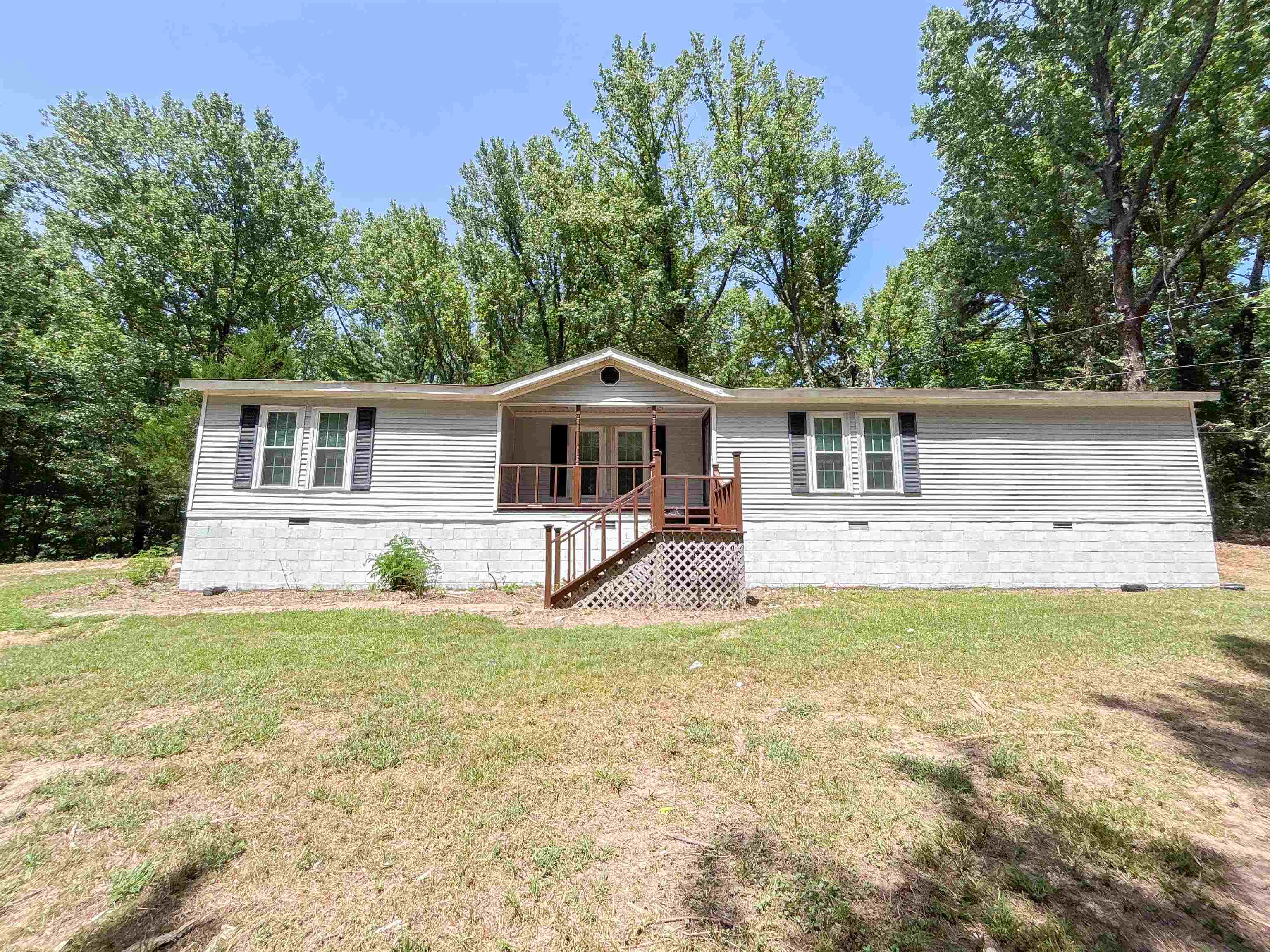 471 Milton Road Millington, TN 38053 - Photo 1 of 30 Light gray horizontal siding with a central covered porch, wood-tone railings, and dark louvered shutters