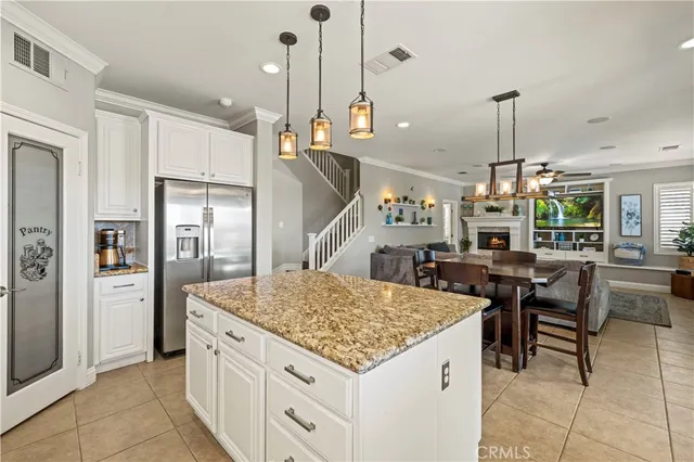 a kitchen with stainless steel appliances kitchen island granite countertop a table chairs and a refrigerator
