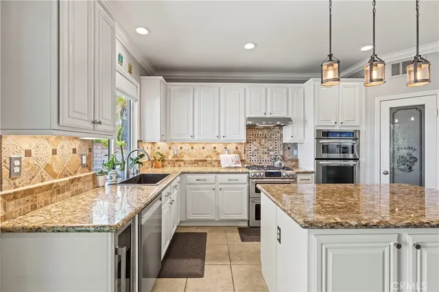 a kitchen with kitchen island granite countertop a sink stove cabinets and refrigerator