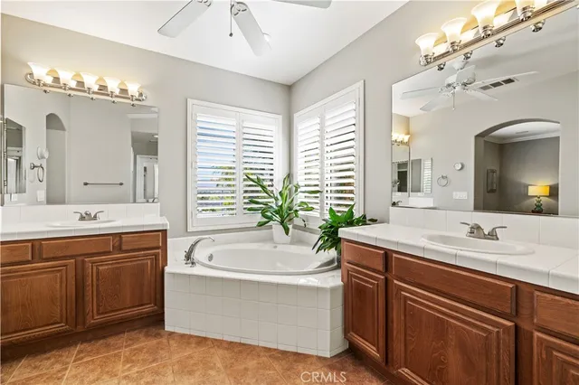 a bathroom with a tub a double vanity sink a large mirror and a bathtub next to a window
