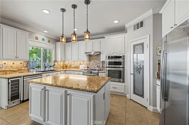 a kitchen with kitchen island granite countertop a sink a counter and stainless steel appliances