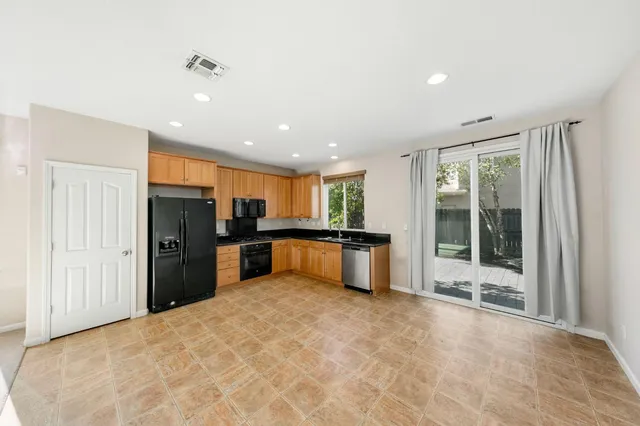 a large kitchen with stainless steel appliances kitchen island granite countertop a refrigerator and a sink