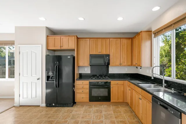 a kitchen with stainless steel appliances granite countertop a stove a sink and a refrigerator