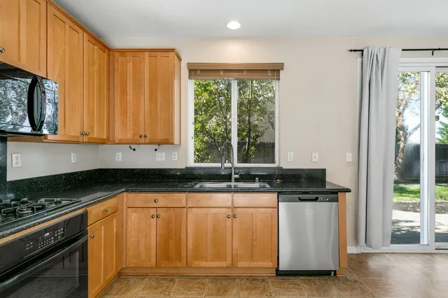 a kitchen with granite countertop a sink a stove and cabinets
