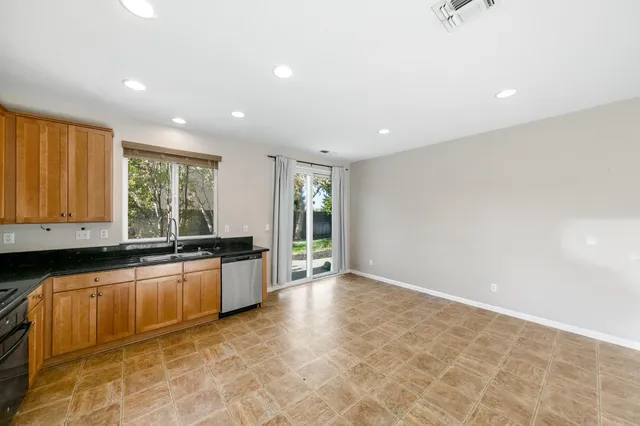 a large kitchen with granite countertop a stove a sink a window and dining table