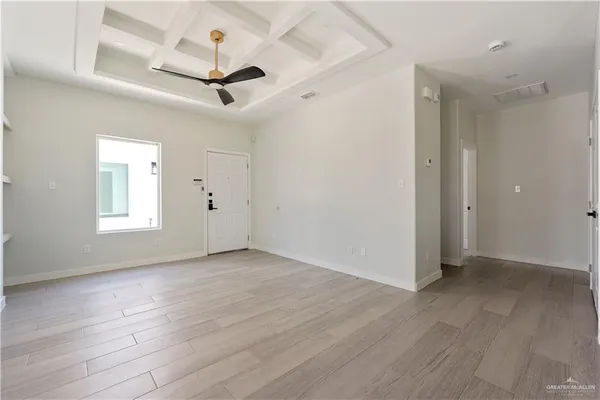 an empty room with wooden floor ceiling fan and windows