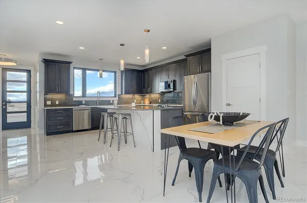 a kitchen with a dining table chairs and refrigerator