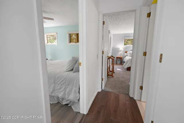 a view of a hallway with wooden floor a bedroom and a bed