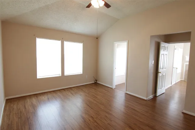 an empty room with wooden floor and windows
