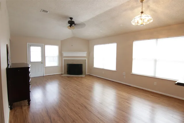 an empty room with wooden floor windows and a fireplace