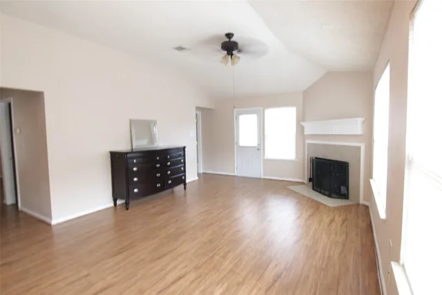 an empty room with wooden floor fireplace and windows